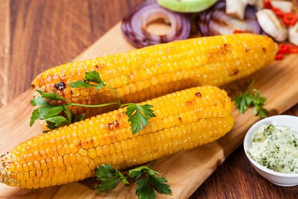 Grilled corn cobs on wooden plate